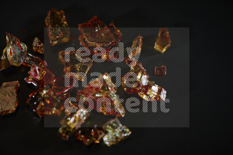 Transparent orange fragments of glass scattered on a black background