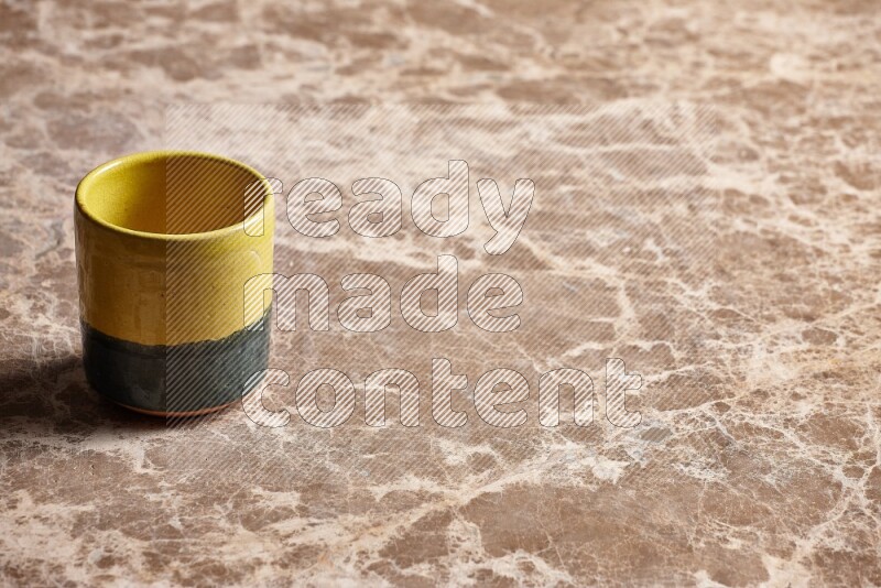 A multicolored pottery cup on beige marble background