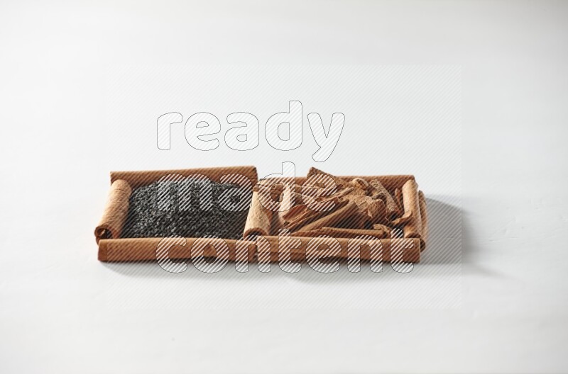 مربعان من أعواد القرفة ممتلئان بحبة البركة السوداء والقرفة علي خلفية بيضاء