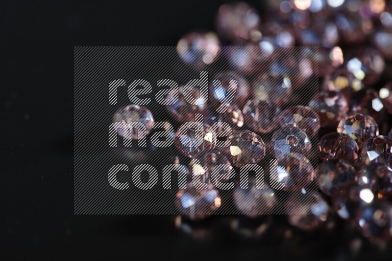 Rose transparent crystal beads scattered on a black background