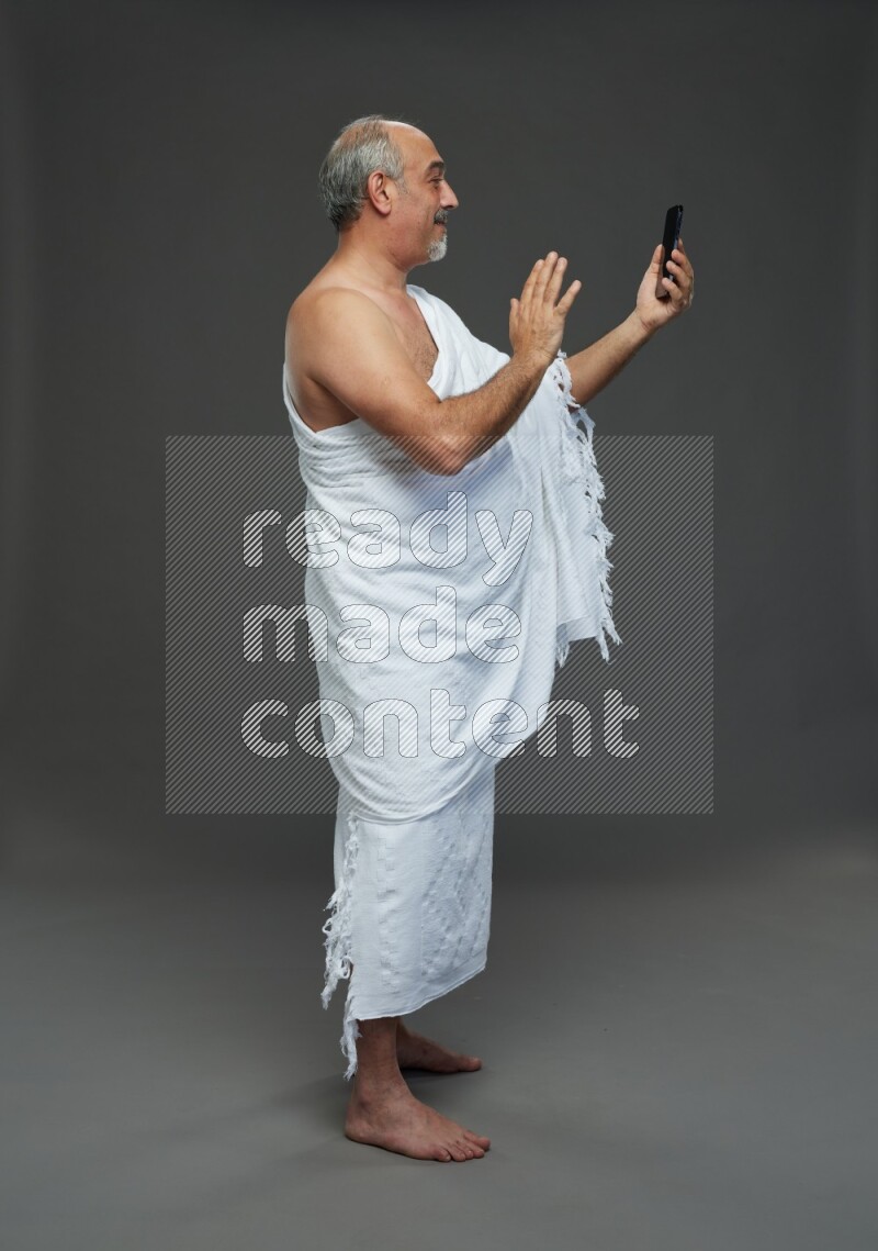 A man wearing Ehram Standing taking selfie on gray background