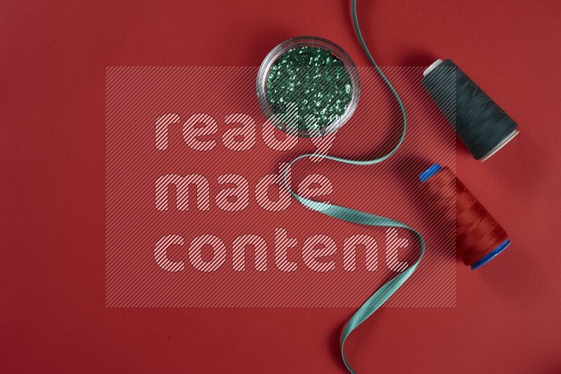 A green and red collection of sewing and tailoring tools arranged on a red background