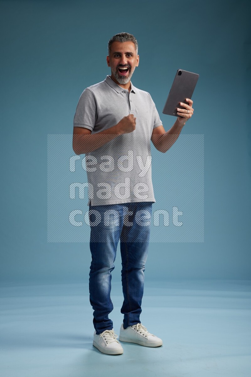 Man Standing working on tablet on blue background