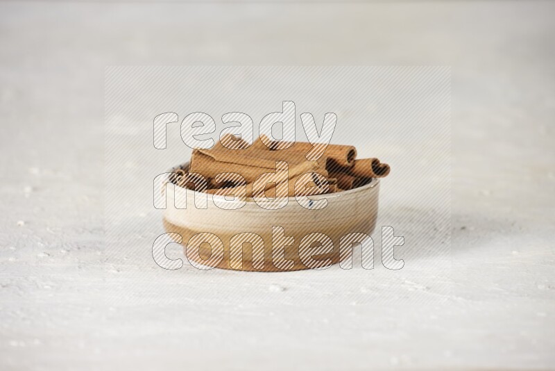Cinnamon sticks in a ceramic bowl in different angles on white background