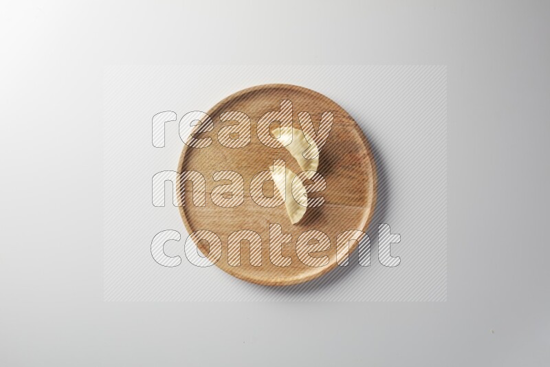 Two Sambosas on a wooden round plate on a white background