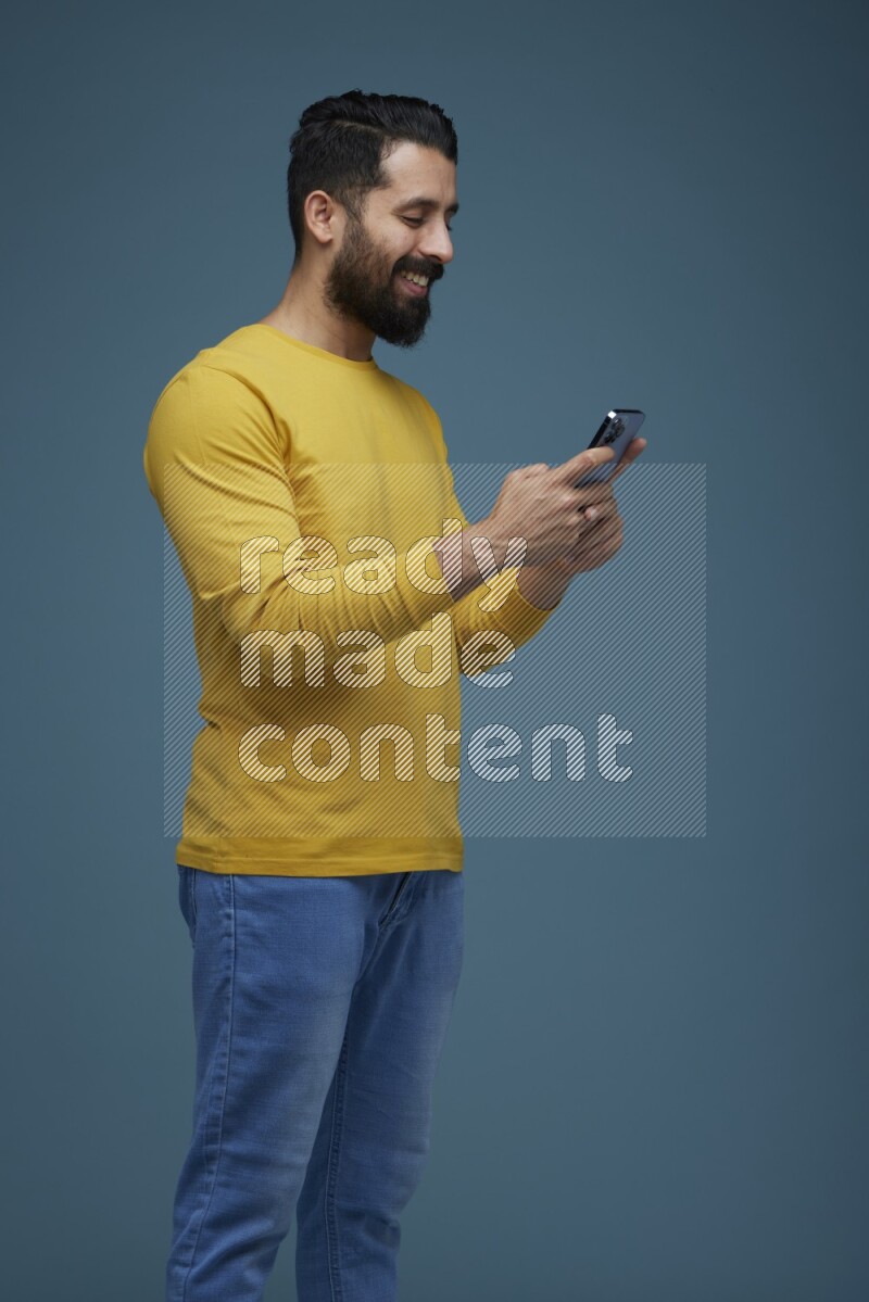 Man typing on his phone in a blue background wearing a yellow shirt