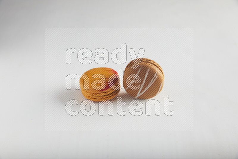 45º Shot of of two assorted Brown Irish Cream, and Orange Exotic macarons on white background