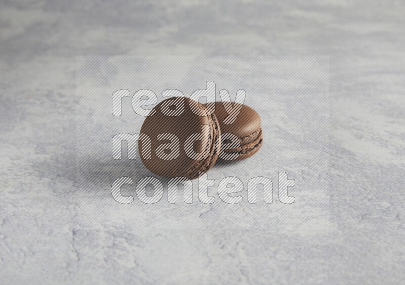 45º Shot of two Brown Dark Chocolate macarons  on white  marble background