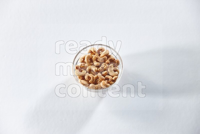 A glass bowl full of cashews on a white background in different angles