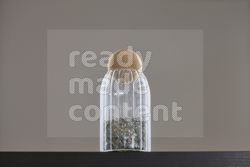 Sequins in a glass jar on black background