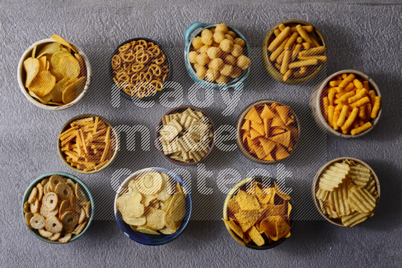 Assorted snacks in pottery bowls on grey background