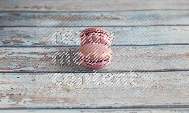 45º Shot of two Purple Strawberry macarons on light blue wooden background