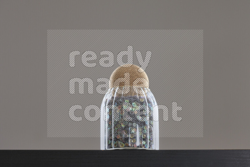 Sequins in a glass jar on black background