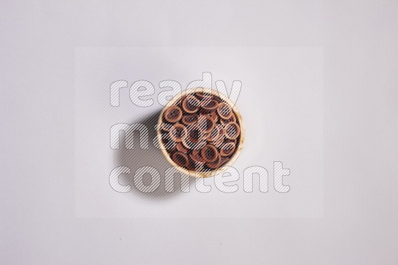 Colored buttons in a beige pottery bowl on grey background