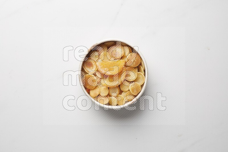 Top-view shot of orange candy cereal pancakes in a round bowl on white background