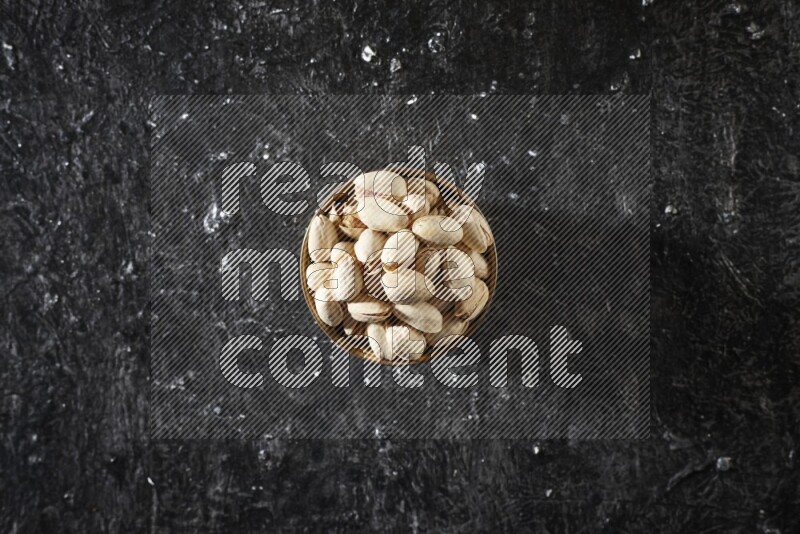 Nuts in a metal bowl in a dark setup