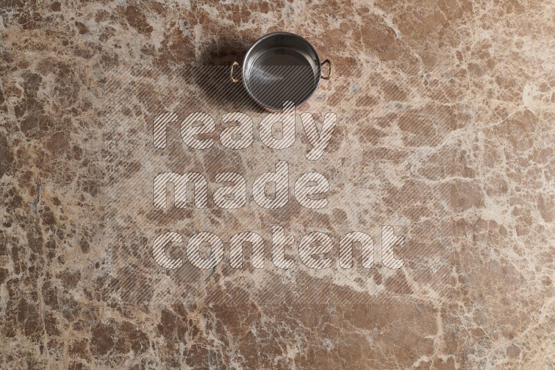 وعاء نحاسي صغير على خلفية من الرخام البيج