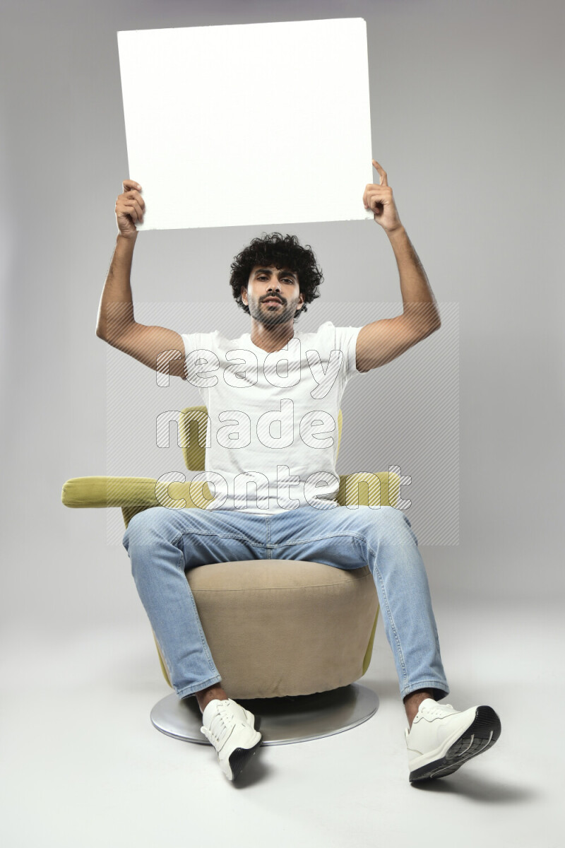 A man wearing casual sitting on a chair holding a white board on white background