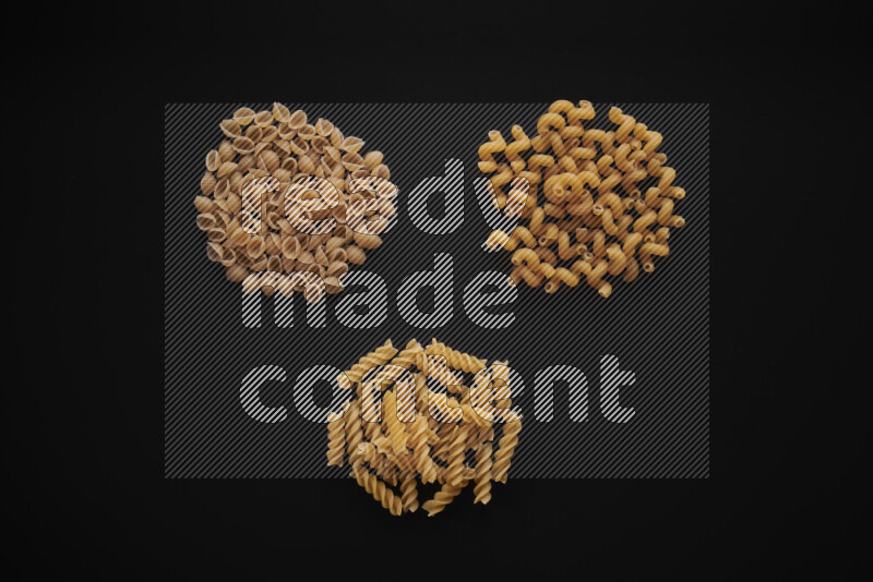 Different pasta types in bunches on black background