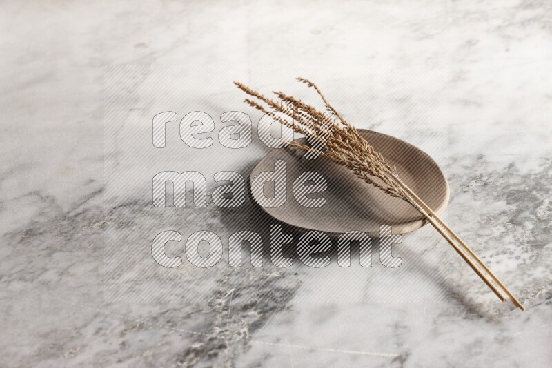 Wheat stalks on multicolored pottery plate on grey marble background