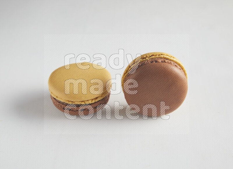45º Shot of two Yellow and Brown Chai Latte macarons on white background