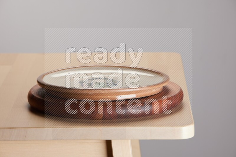multi-colored pottery Plate placed on a dark colored wooden tray on the edge of wooden table