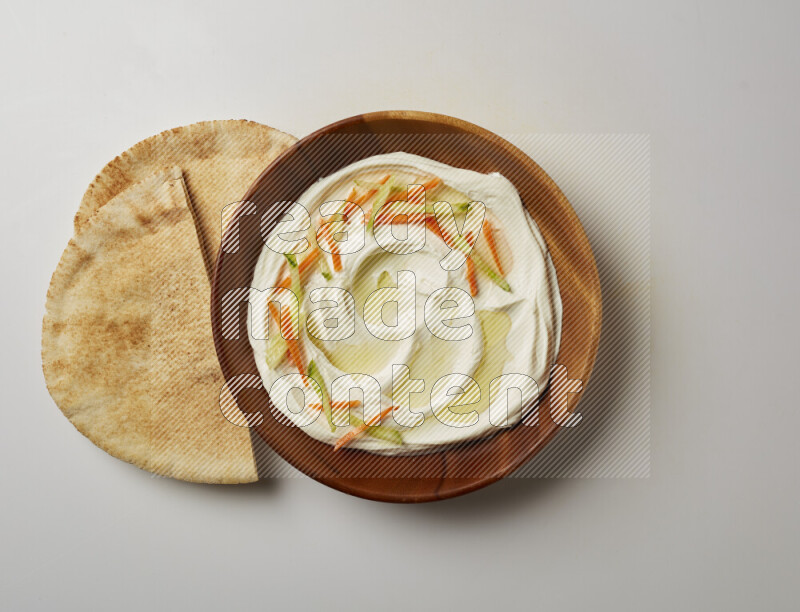 Lebnah garnished with sliced carrots & cucumber in a wooden plate on a white background