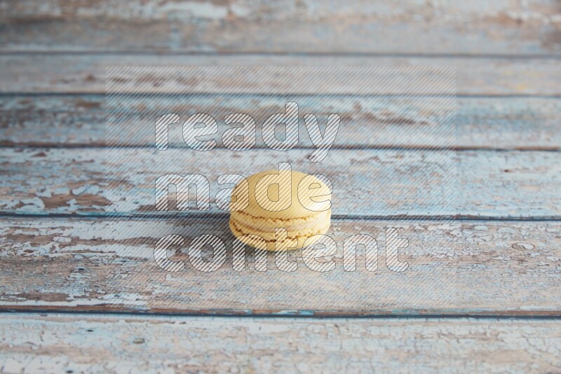 45º Shot of Yellow Vanilla macaron on light blue wooden background