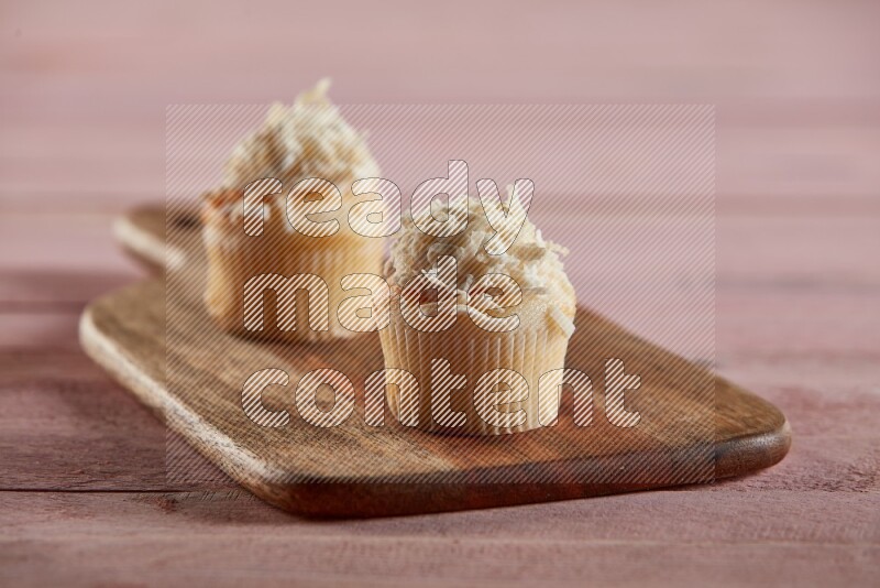 Vanilla mini cupcake topped with coconut on a wooden board