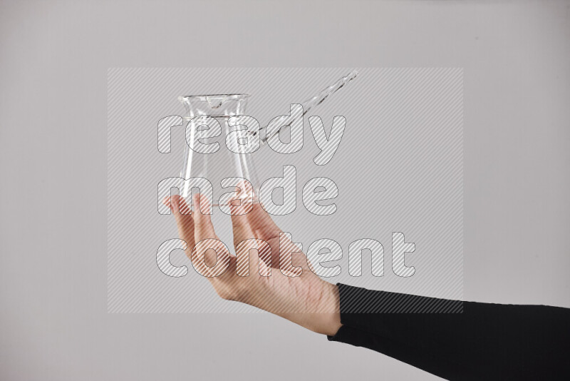 A woman in black abaya holding different glassware in different positions