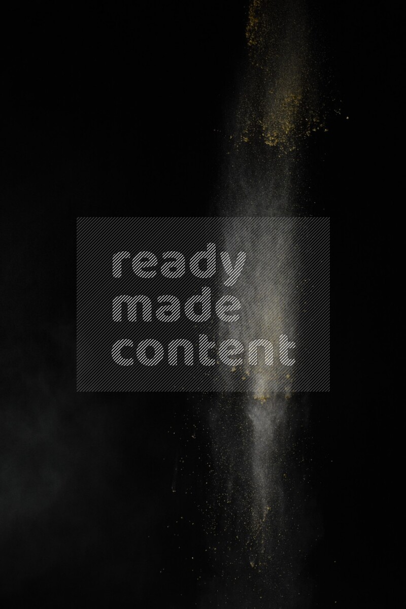 A side view of yellow powder explosion on black background