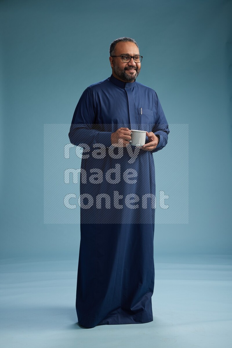 Saudi Man without shimag Standing drinking coffee on blue background