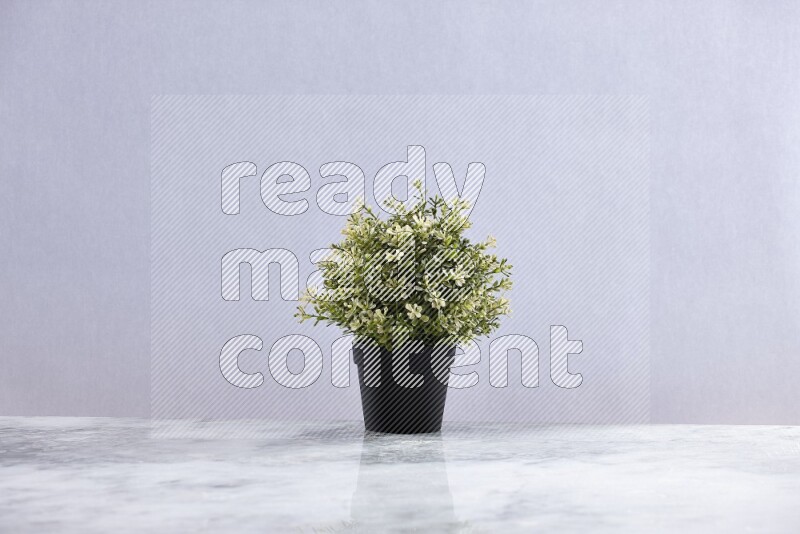 Artificial plant in black pot on grey marble background