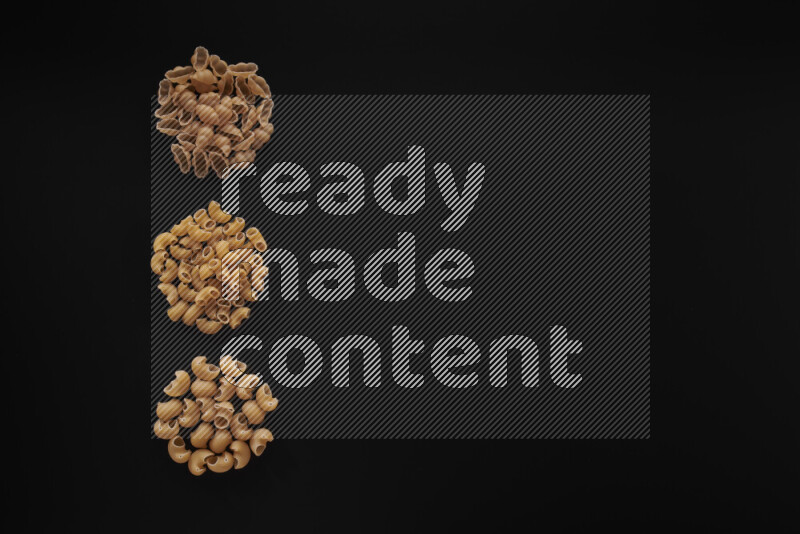 Different pasta types in 3 bunches on black background