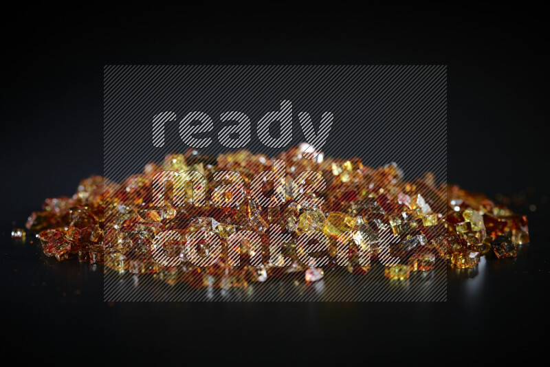 Transparent orange fragments of glass scattered on a black background