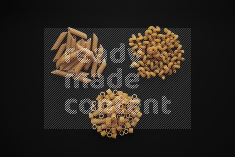 Different pasta types in bunches on black background