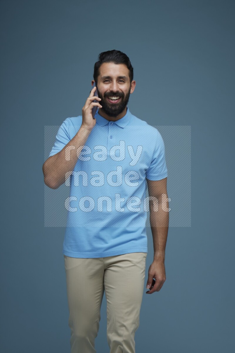 A man having a Call in a blue background wearing a Blue shirt