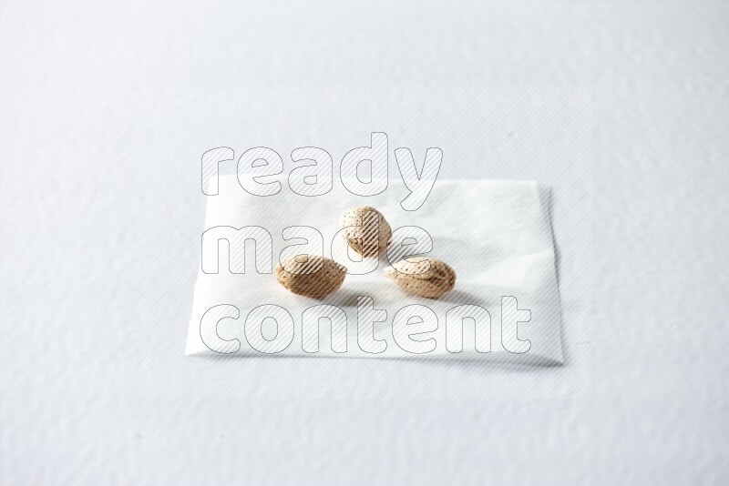 3 almonds on a piece of paper on a white background in different angles