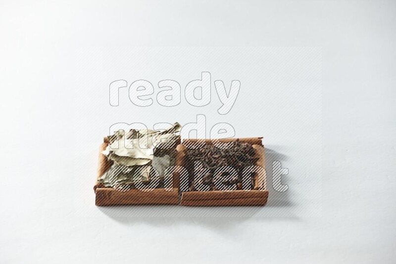 2 squares of cinnamon sticks full of cloves and bay laurel leaves on white flooring