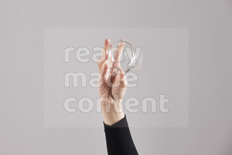 A woman in black abaya holding different glassware in different positions