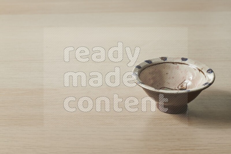A decorative pottery bowl on light wooden background