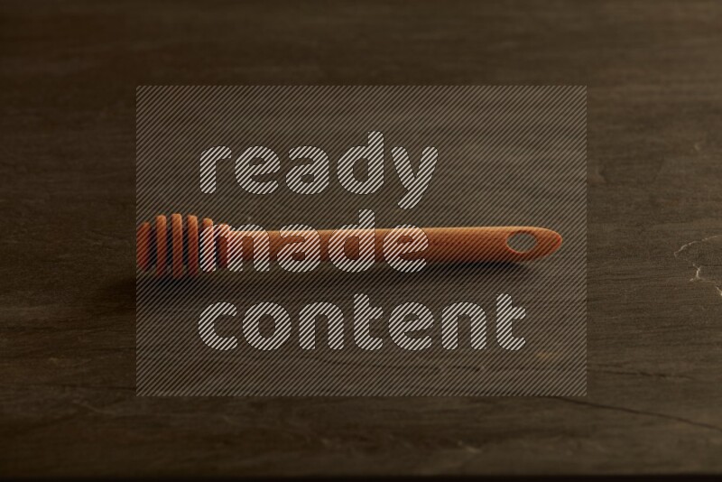 Wooden honey dipper on black slate background