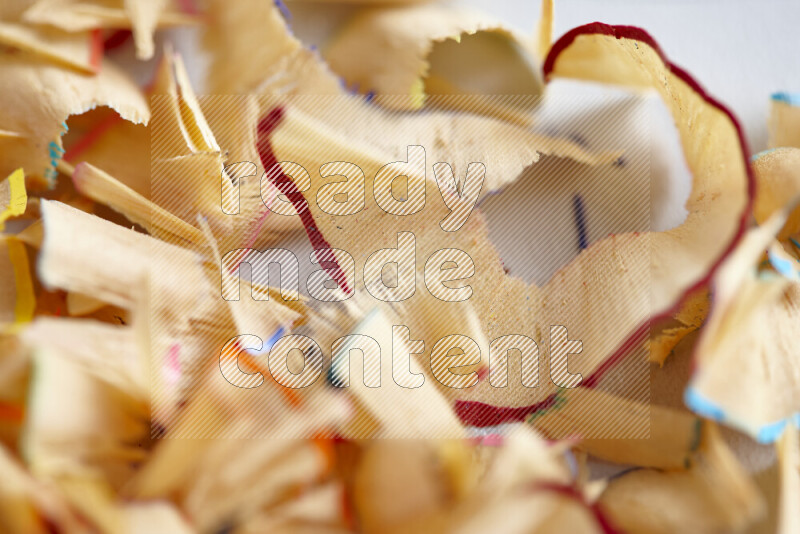 A close-up showing a small pile of pencil shavings with varied color edges on grey background