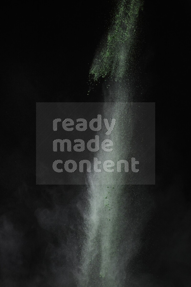 A side view of green powder explosion on black background