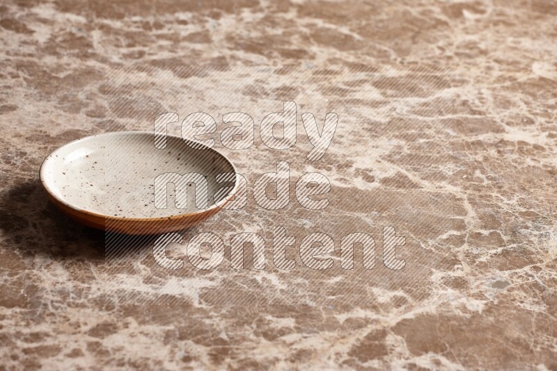 A multicolored pottery plate on beige marble background