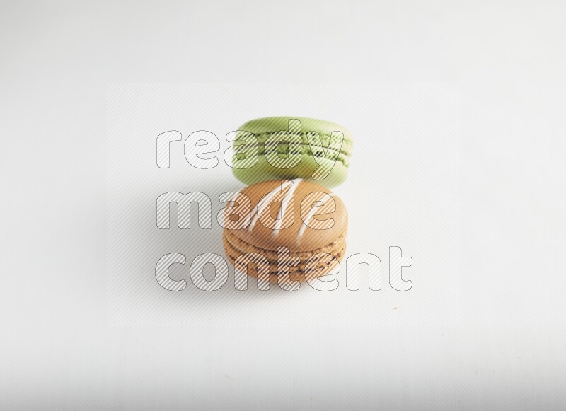 45º Shot of of two assorted Brown Irish Cream, and Green Pistachio macarons on white background