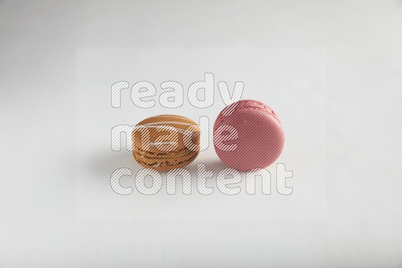45º Shot of of two assorted Brown Irish Cream, and Pink Raspberry macarons on white background