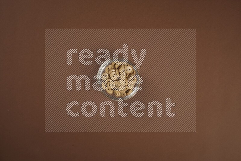 Brown buttons in a glass bowl on brown background