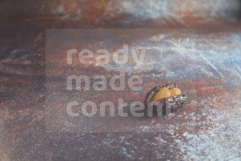 one almond stuffed madjoul date on a rustic reddish background