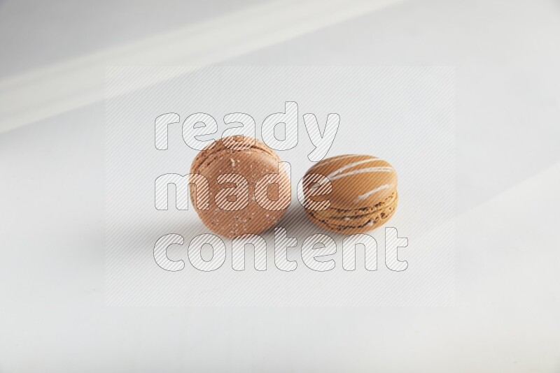 45º Shot of of two assorted Brown Irish Cream, and Brown Hazelnuts macarons on white background